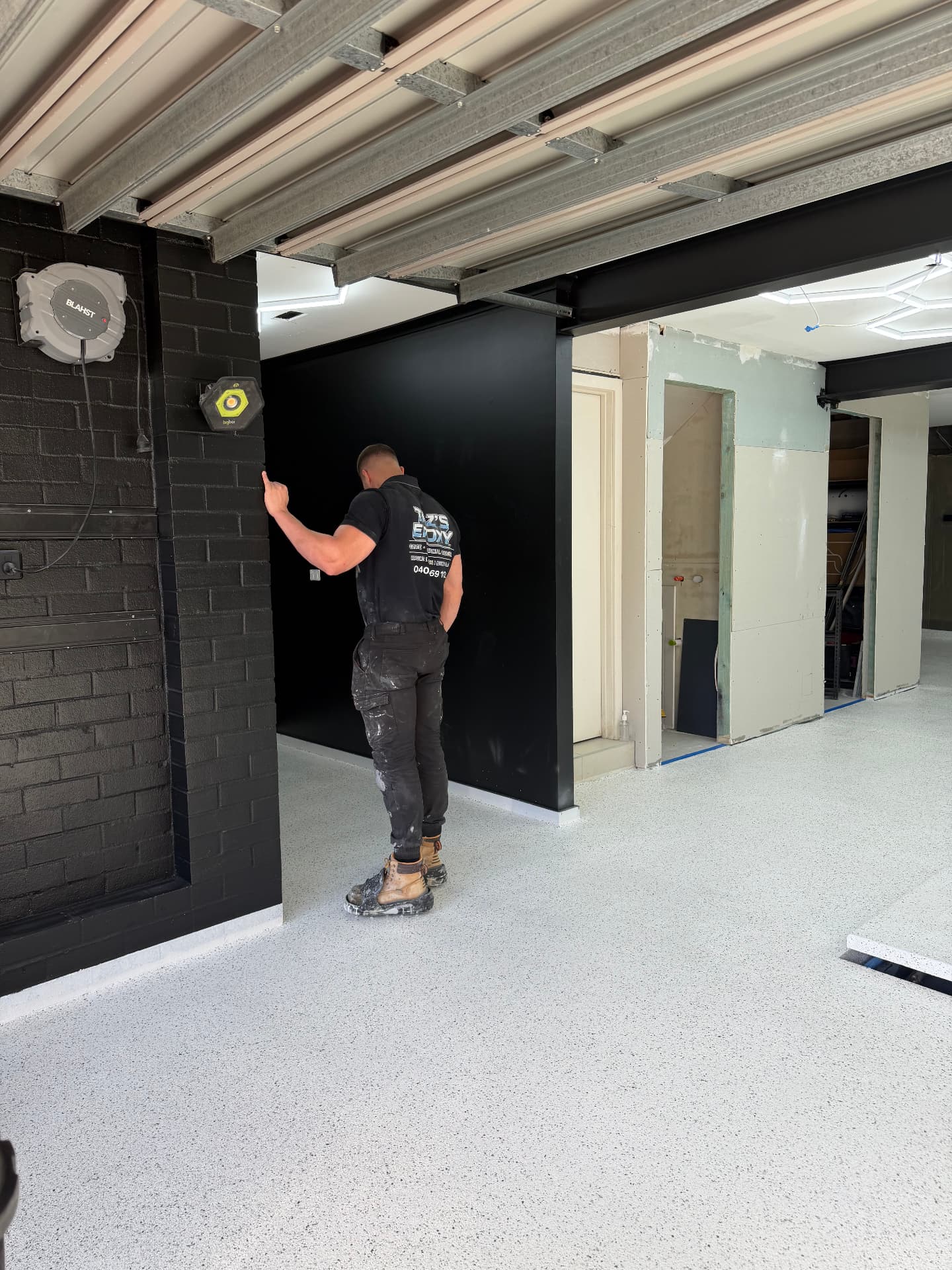 Taz of Taz's Epoxy Co on site in front of a finished white flake epoxy floor