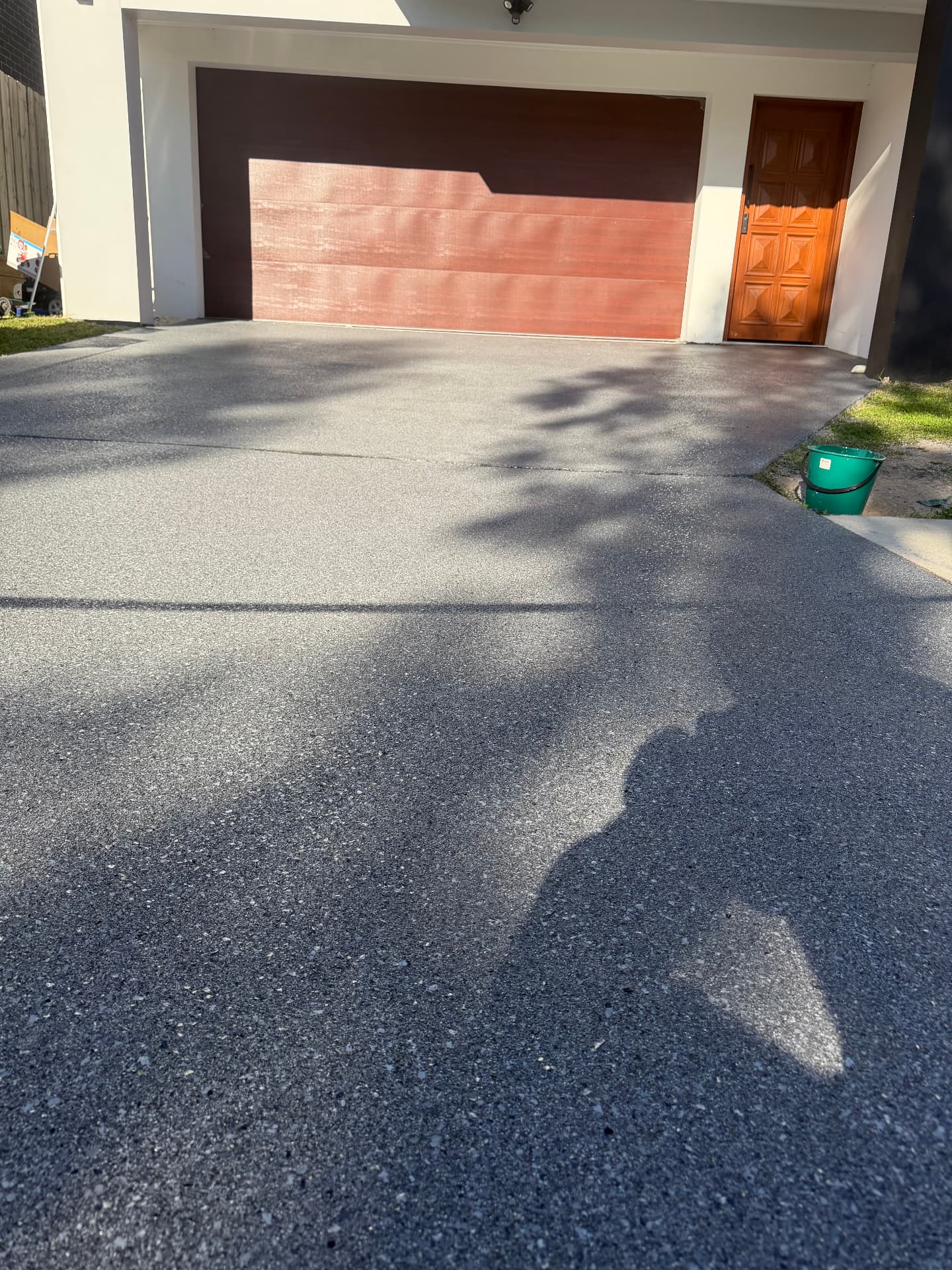 Charcoal flake epoxy driveway leading to a double garage